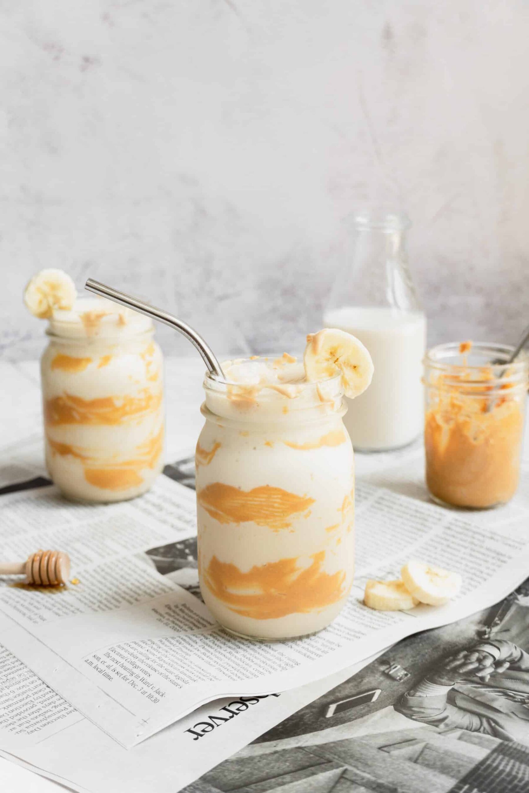 Peanut butter banana smoothies in mason jars with a bottle of milk.