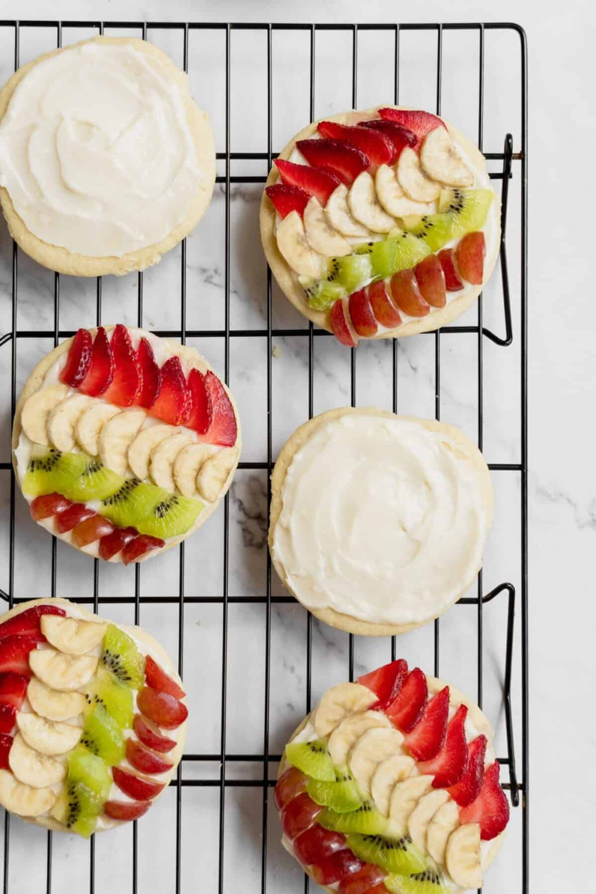 Fruit pizza cookies on a cooling rack on a white background.