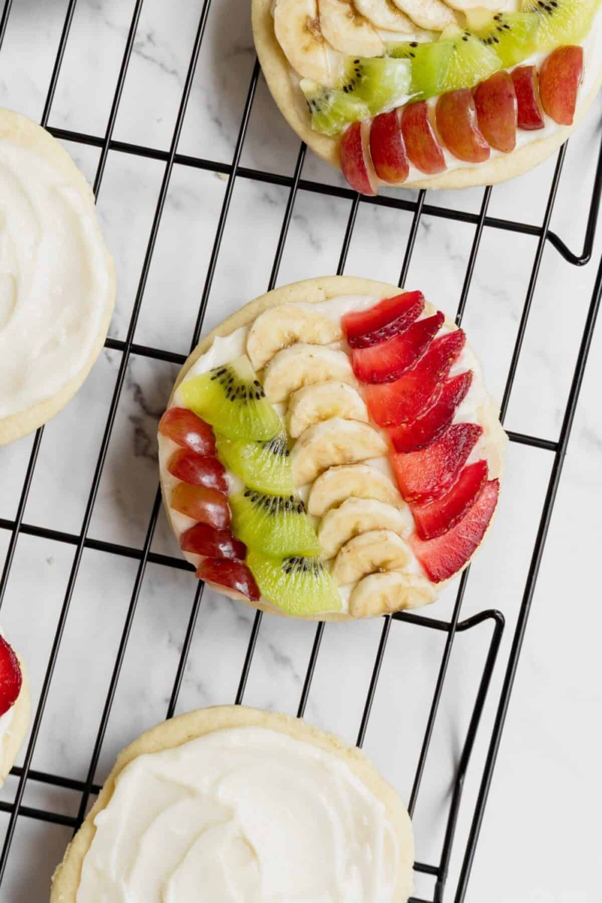 Mini fruit pizzas with cream cheese frosting, grapes, kiwi, bananas, and strawberries.