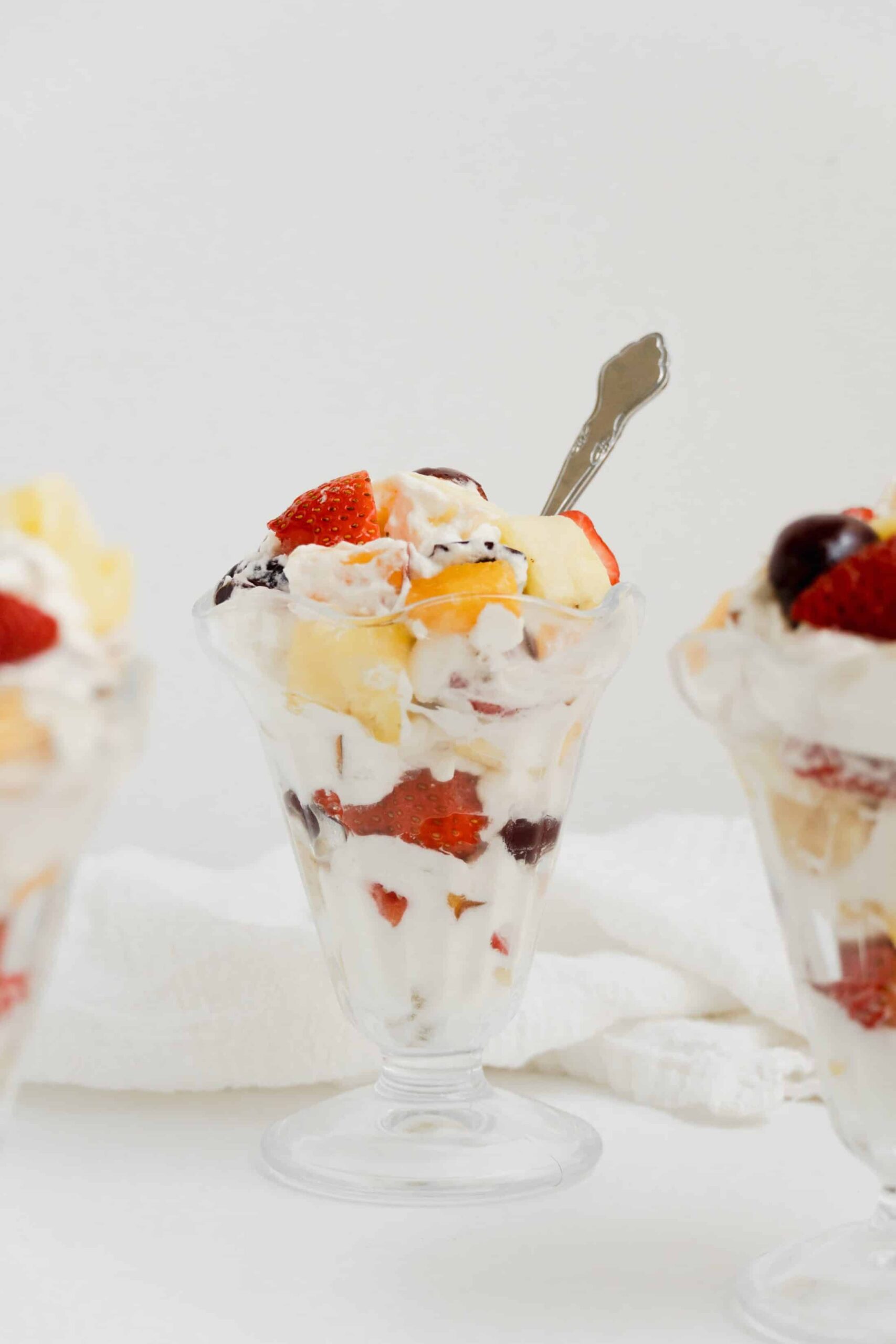 Whipped cream fruit salad with strawberries, pineapple, bananas, peaches, and cherries.