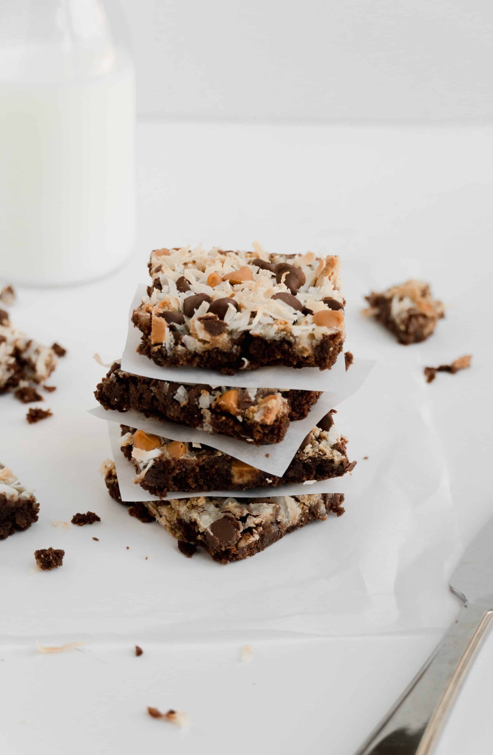 Magic brownie bars cut and stacked with parchment paper between each square.