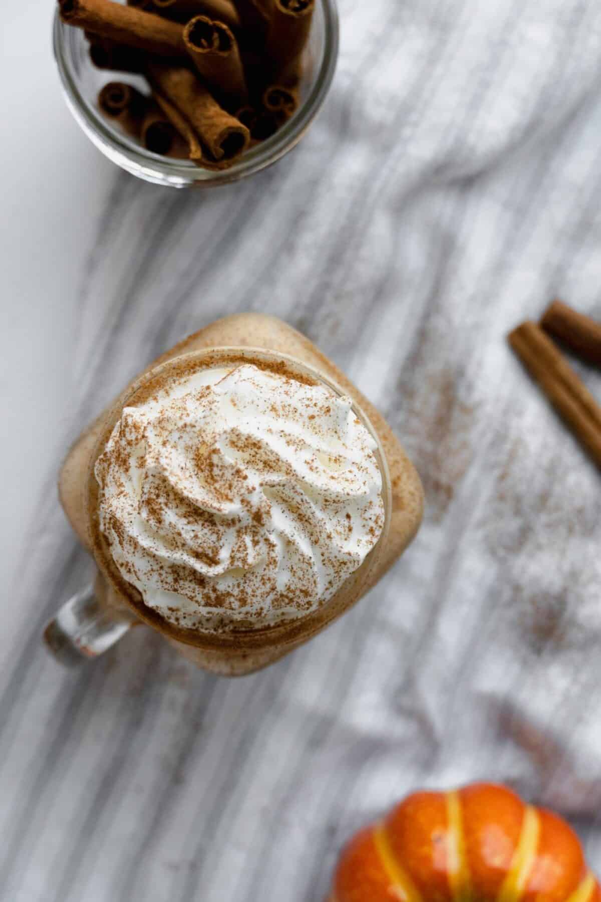 Top down photo of a healthy pumpkin pie shake with whipped cream and cinnamon on top.