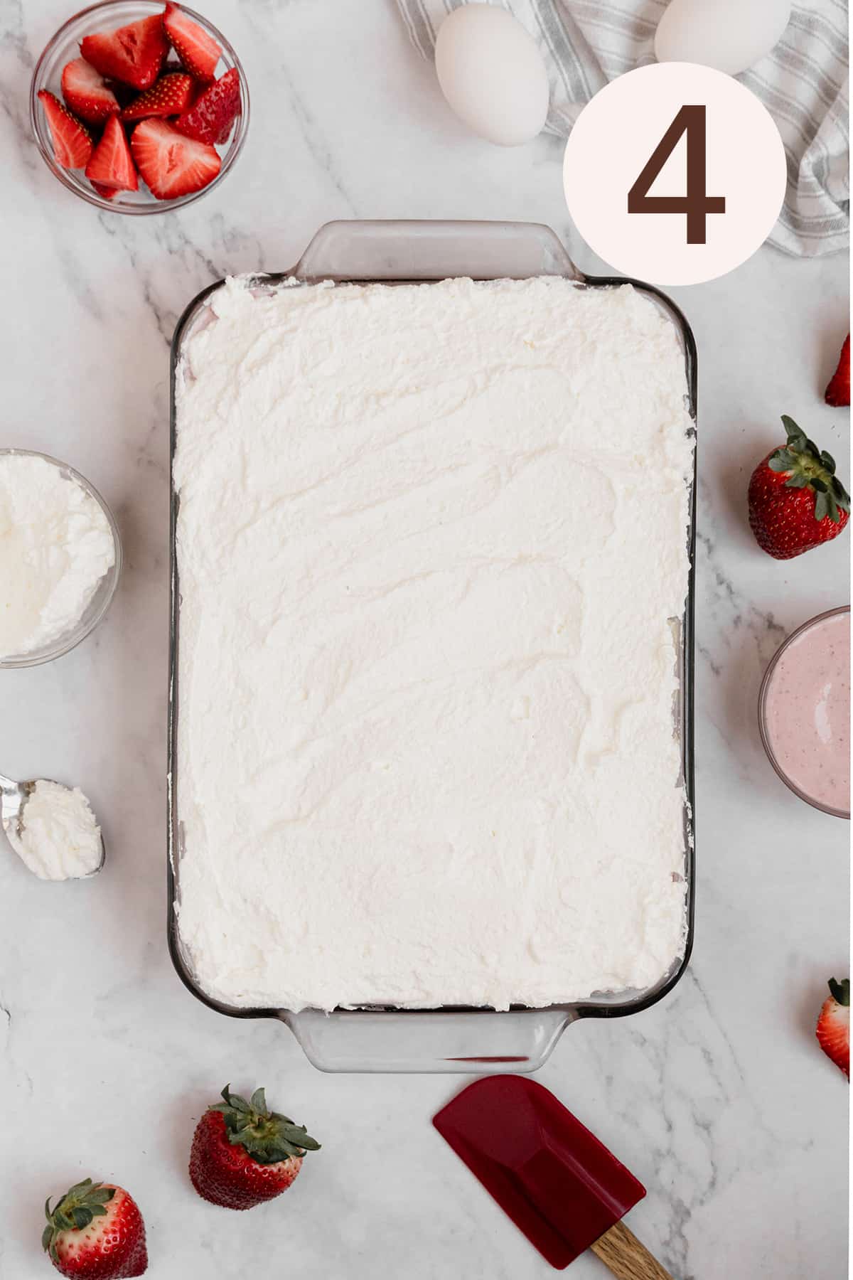 Adding a layer of whipped cream frosting onto the cake.